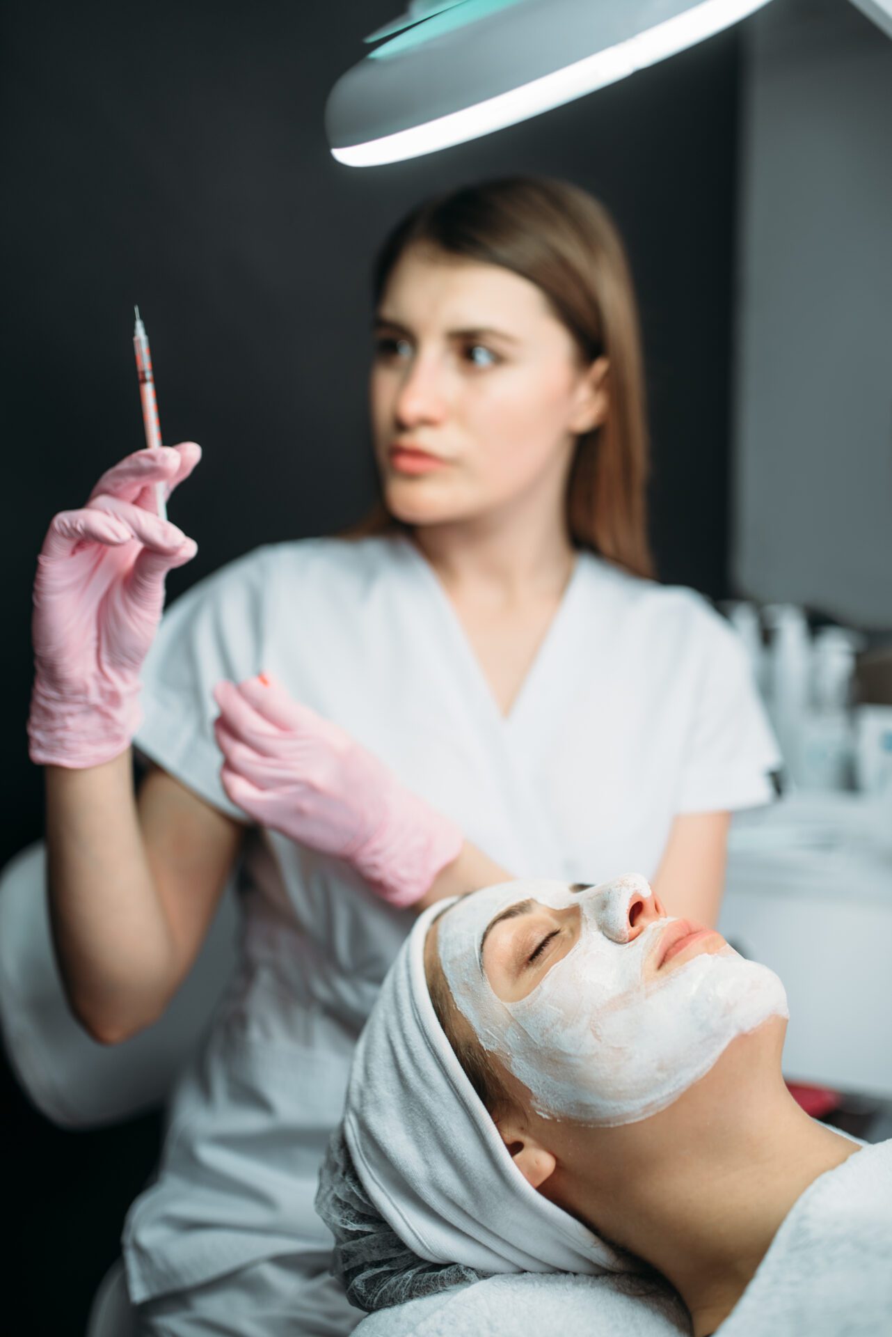 Beautician with syringe in hands, botox injection red-light-bed