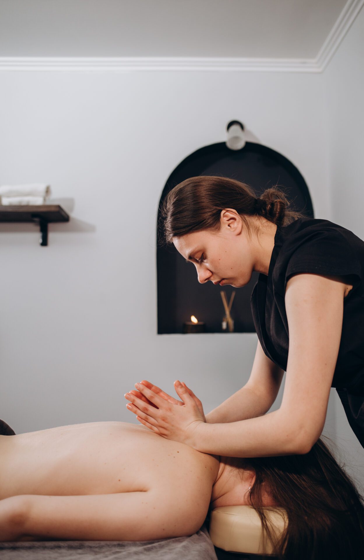 Anonymous female masseur pressing on back of client with elbows while doing traditional massage in light modern clinic You, Naturally Better